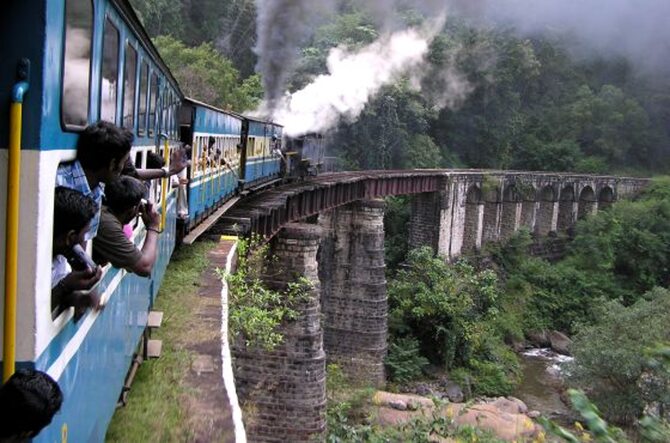 Widok boku pociągu jadącego po wysokim wiadukcie i głów pasażerów wystających z okien